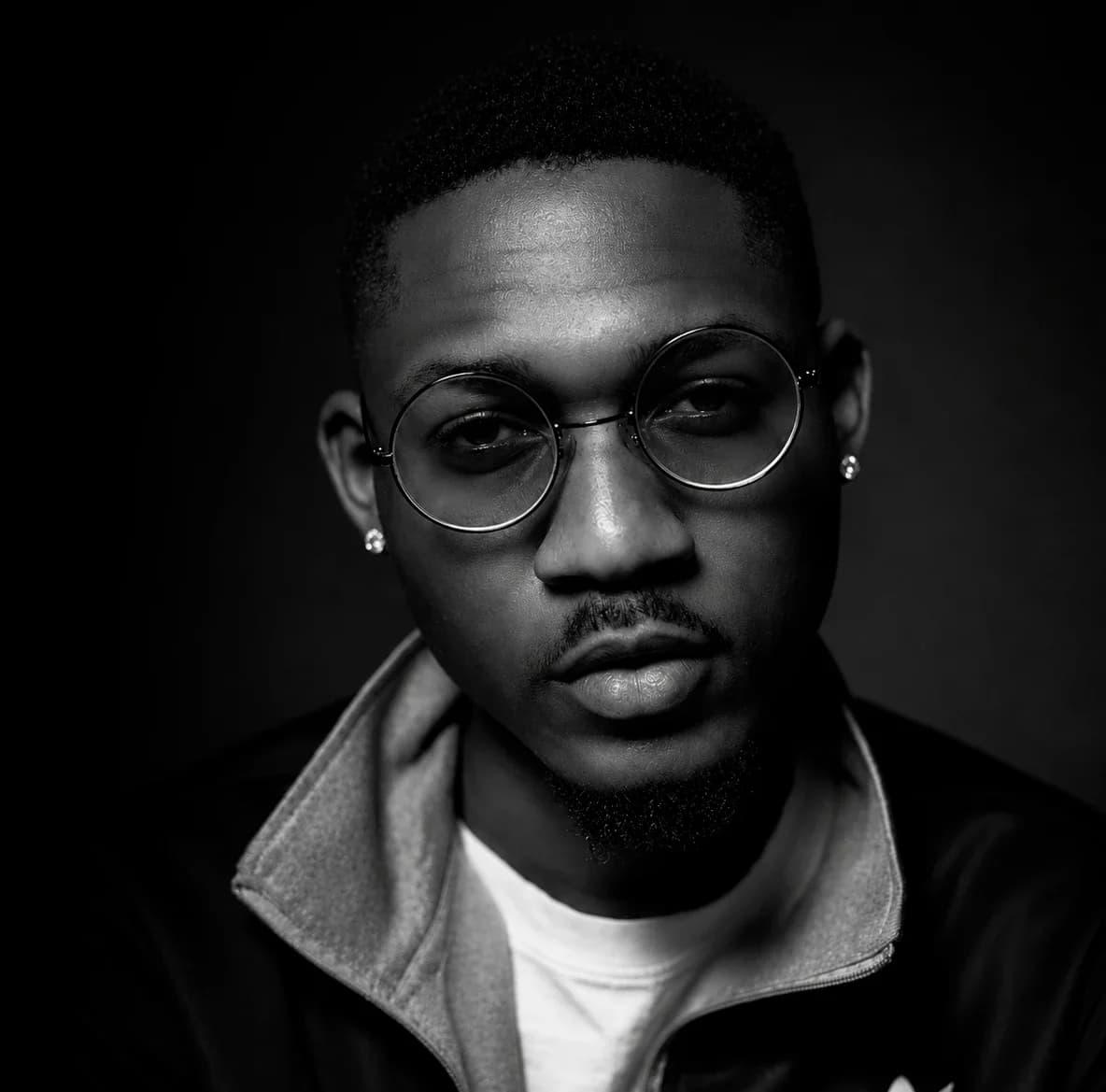 Phantom in black and white, wearing round wire glasses, looking into the camera